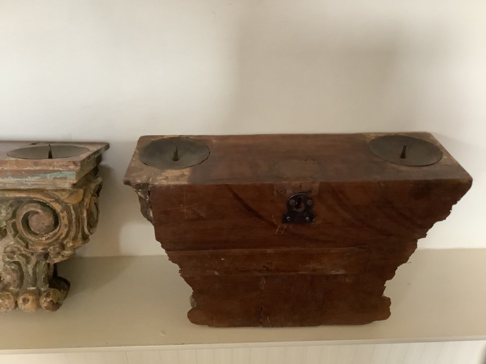 A pair of carved wooden Corinthian architectural capitals featuring acanthus leaf motifs and distressed painted finishes with metal candle inserts on top. View V