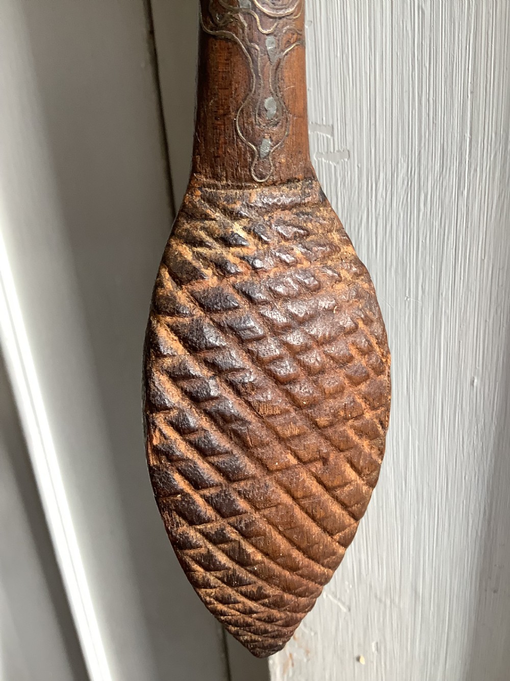 A carved dark wood back scratcher featuring a cross-hatched textured paddle head and delicate floral silver inlay along the slender handle. View III