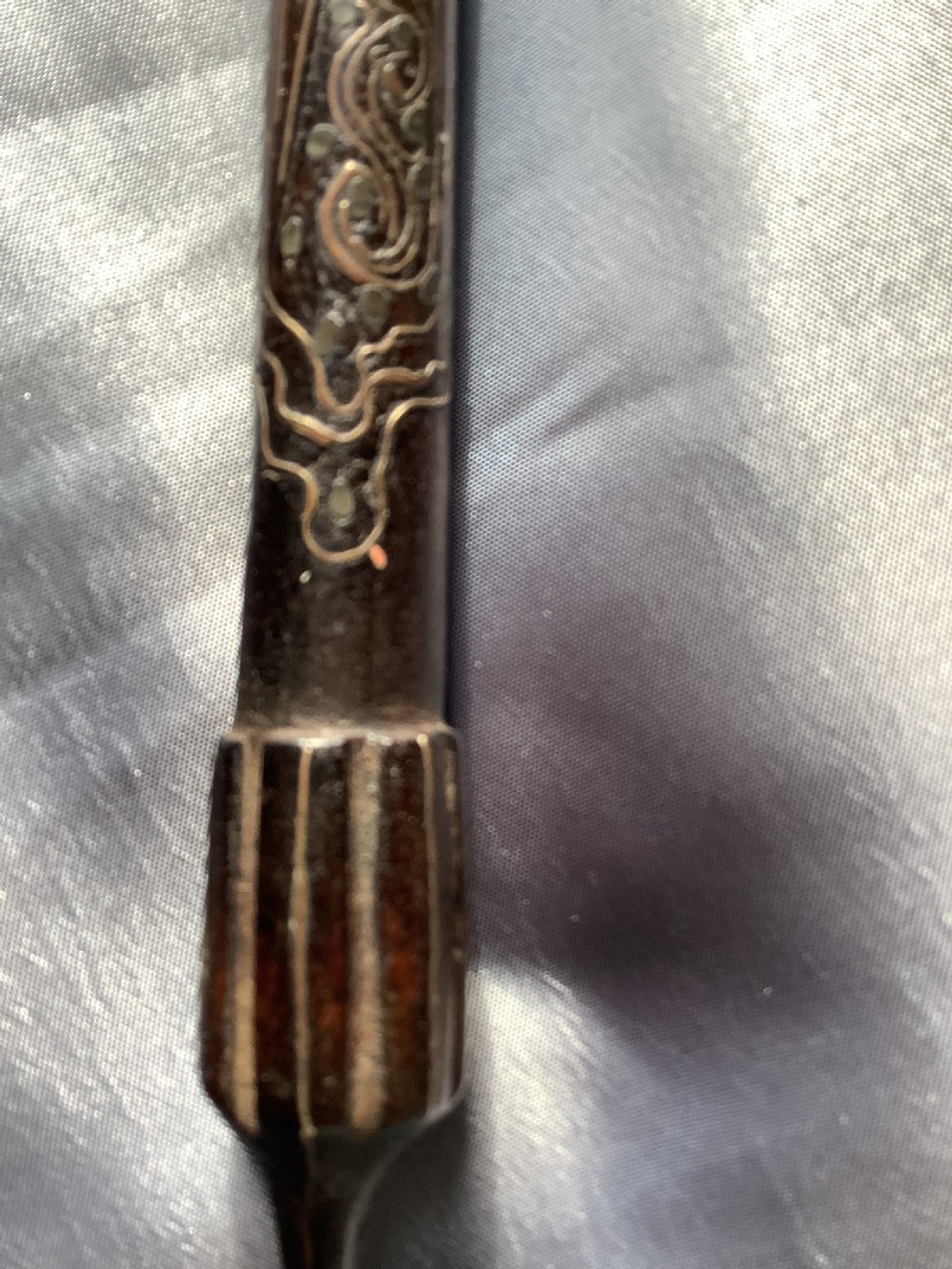 A carved dark wood back scratcher featuring a cross-hatched textured paddle head and delicate floral silver inlay along the slender handle. View VI