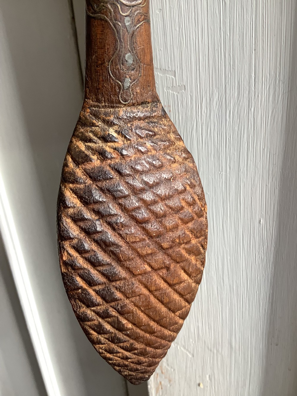A carved dark wood back scratcher featuring a cross-hatched textured paddle head and delicate floral silver inlay along the slender handle. View VII