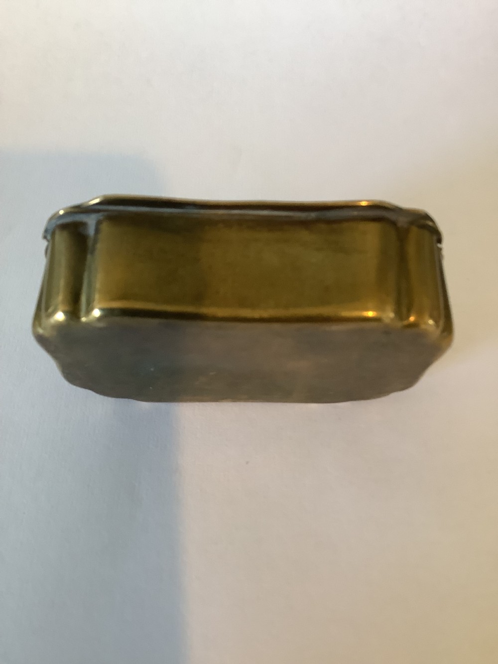 An antique hinged brass snuff box featuring ornate foliate scrollwork engraving and the central inscription reading TAKE A PINCH AND WELCOME. View IX