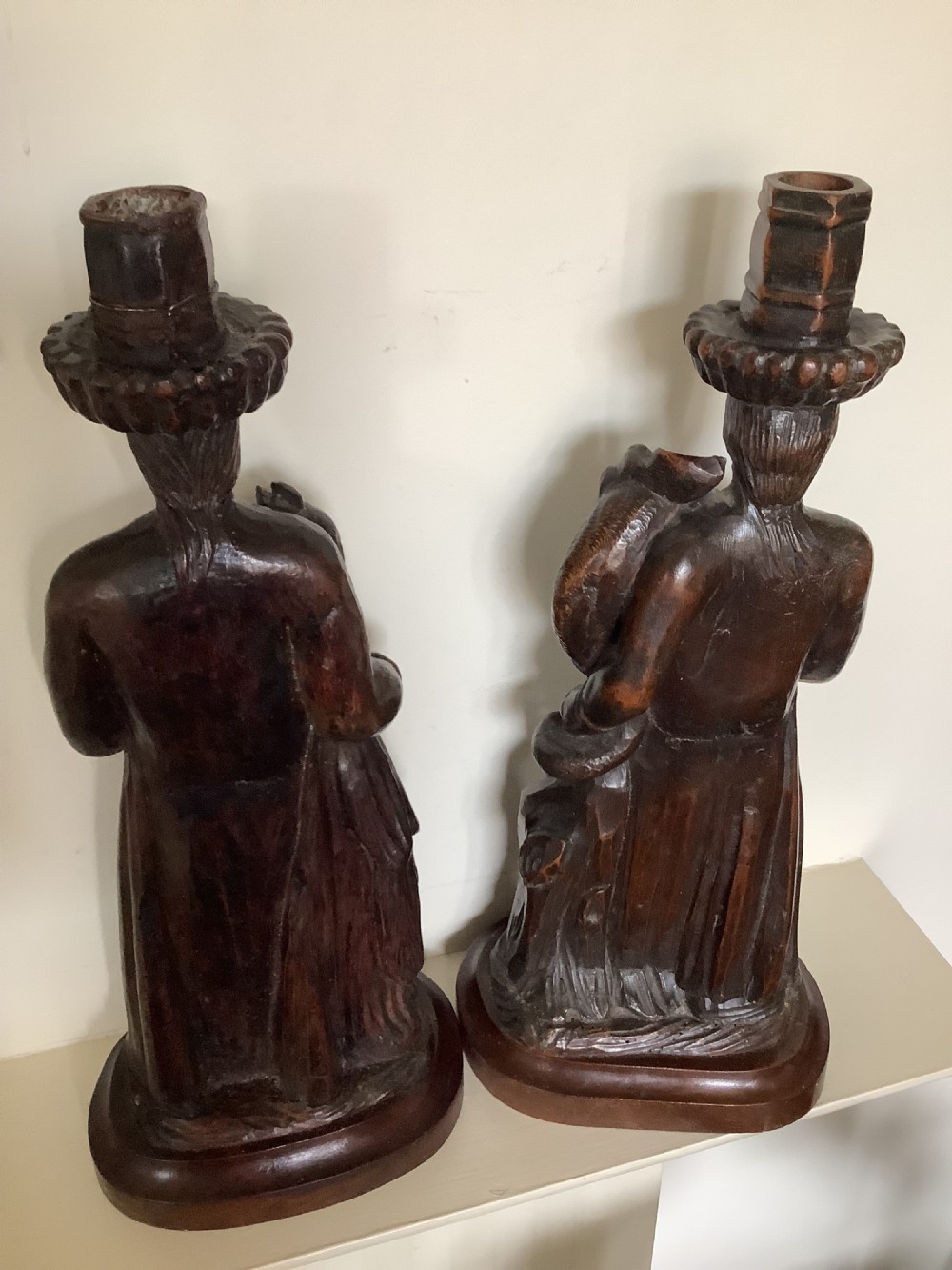 A pair of hand-carved dark wood candlesticks sculpted in the form of standing poachers holding game. View III