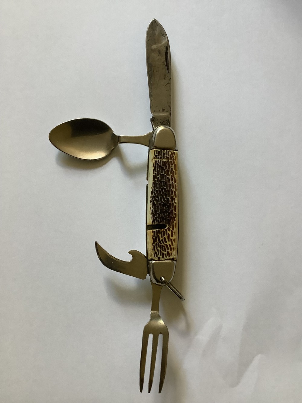 A vintage Jowika multi-blade camping pocket knife featuring an extended main blade, folded steel spoon, fork, bottle opener, and textured brown jigged bone handle scales.