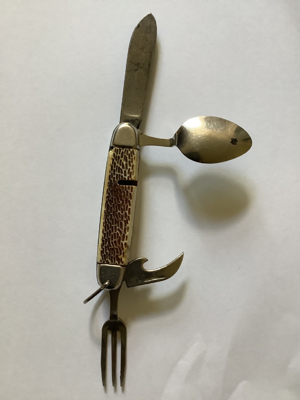 A vintage Jowika multi-blade camping pocket knife featuring an extended main blade, folded steel spoon, fork, bottle opener, and textured brown jigged bone handle scales. View II