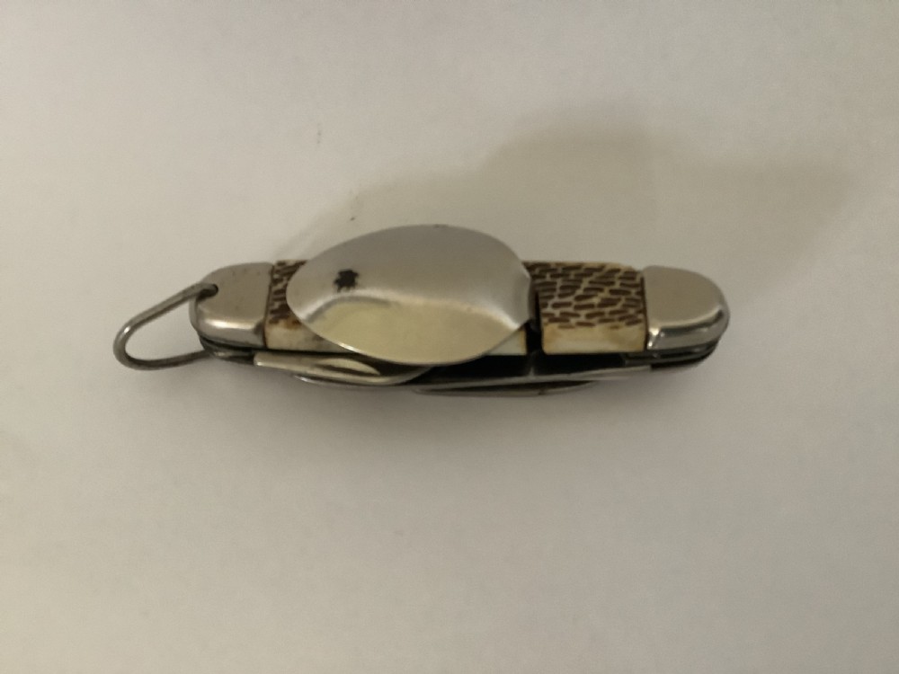 A vintage Jowika multi-blade camping pocket knife featuring an extended main blade, folded steel spoon, fork, bottle opener, and textured brown jigged bone handle scales. View III