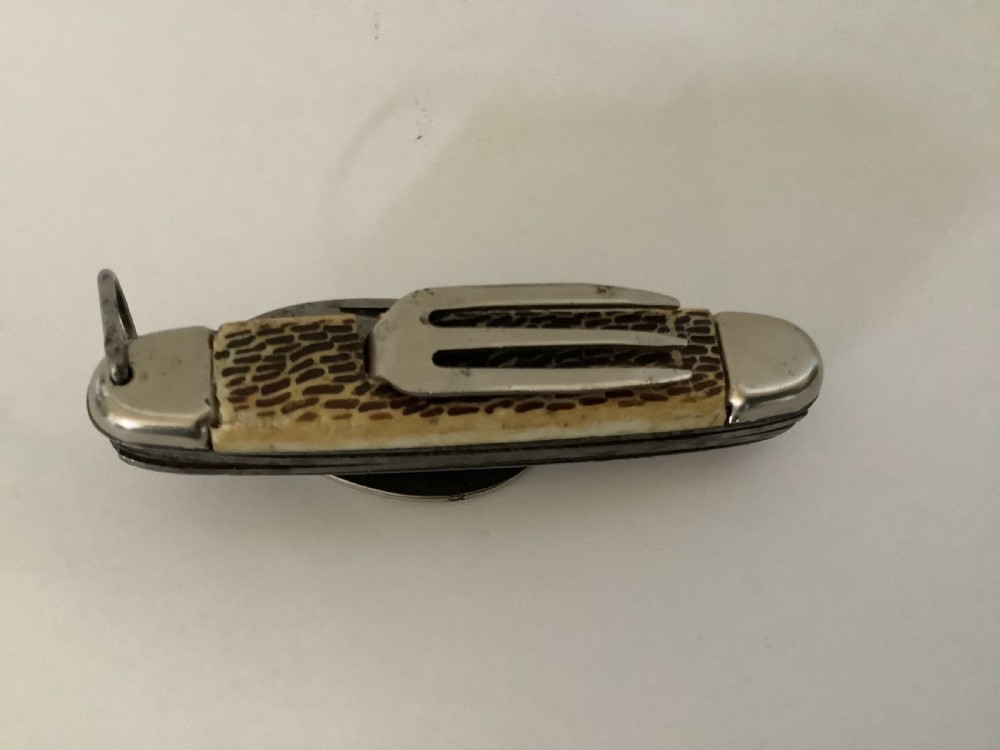 A vintage Jowika multi-blade camping pocket knife featuring an extended main blade, folded steel spoon, fork, bottle opener, and textured brown jigged bone handle scales. View IV