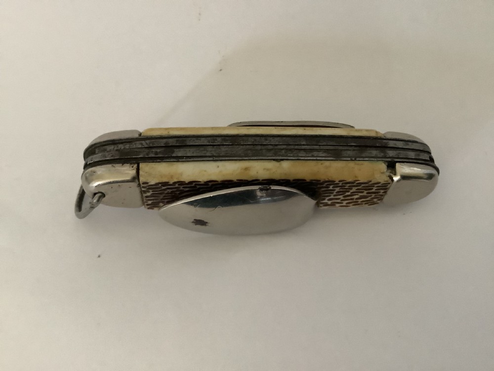 A vintage Jowika multi-blade camping pocket knife featuring an extended main blade, folded steel spoon, fork, bottle opener, and textured brown jigged bone handle scales. View VI