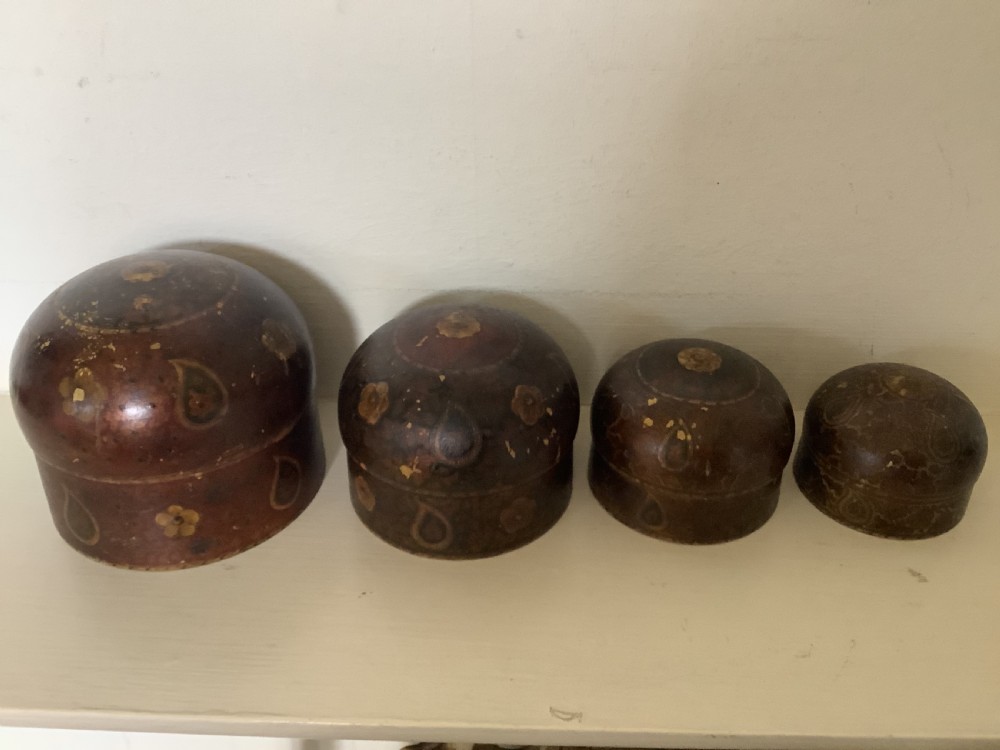 A set of four graduated round Kashmiri boxes painted in dark red and brown with gold floral and paisley motifs. View II