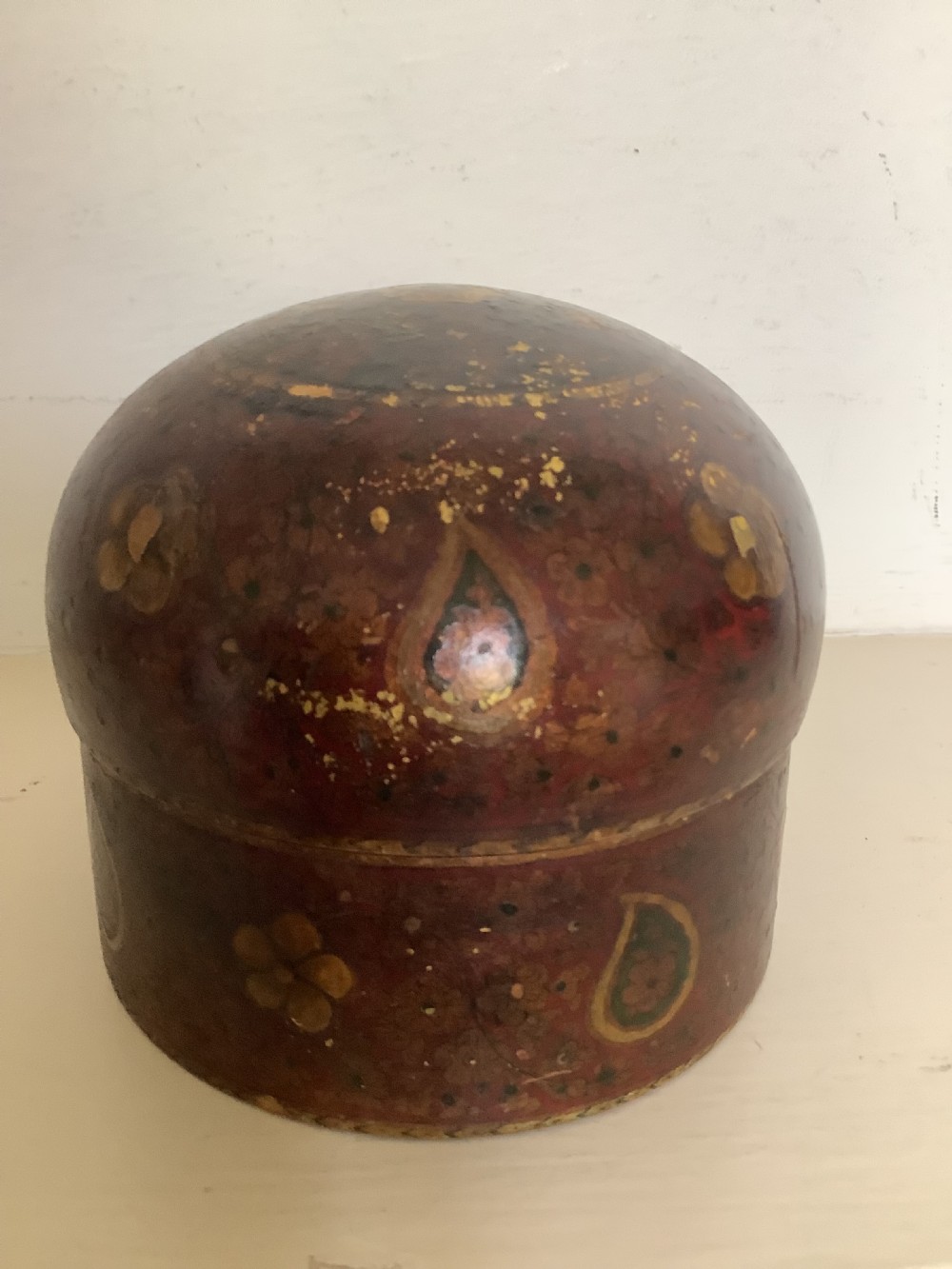 A set of four graduated round Kashmiri boxes painted in dark red and brown with gold floral and paisley motifs. View IV