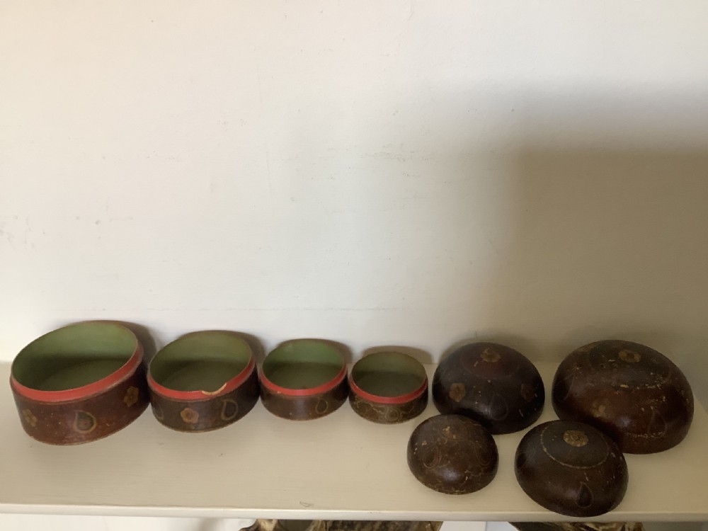 A set of four graduated round Kashmiri boxes painted in dark red and brown with gold floral and paisley motifs. View VI