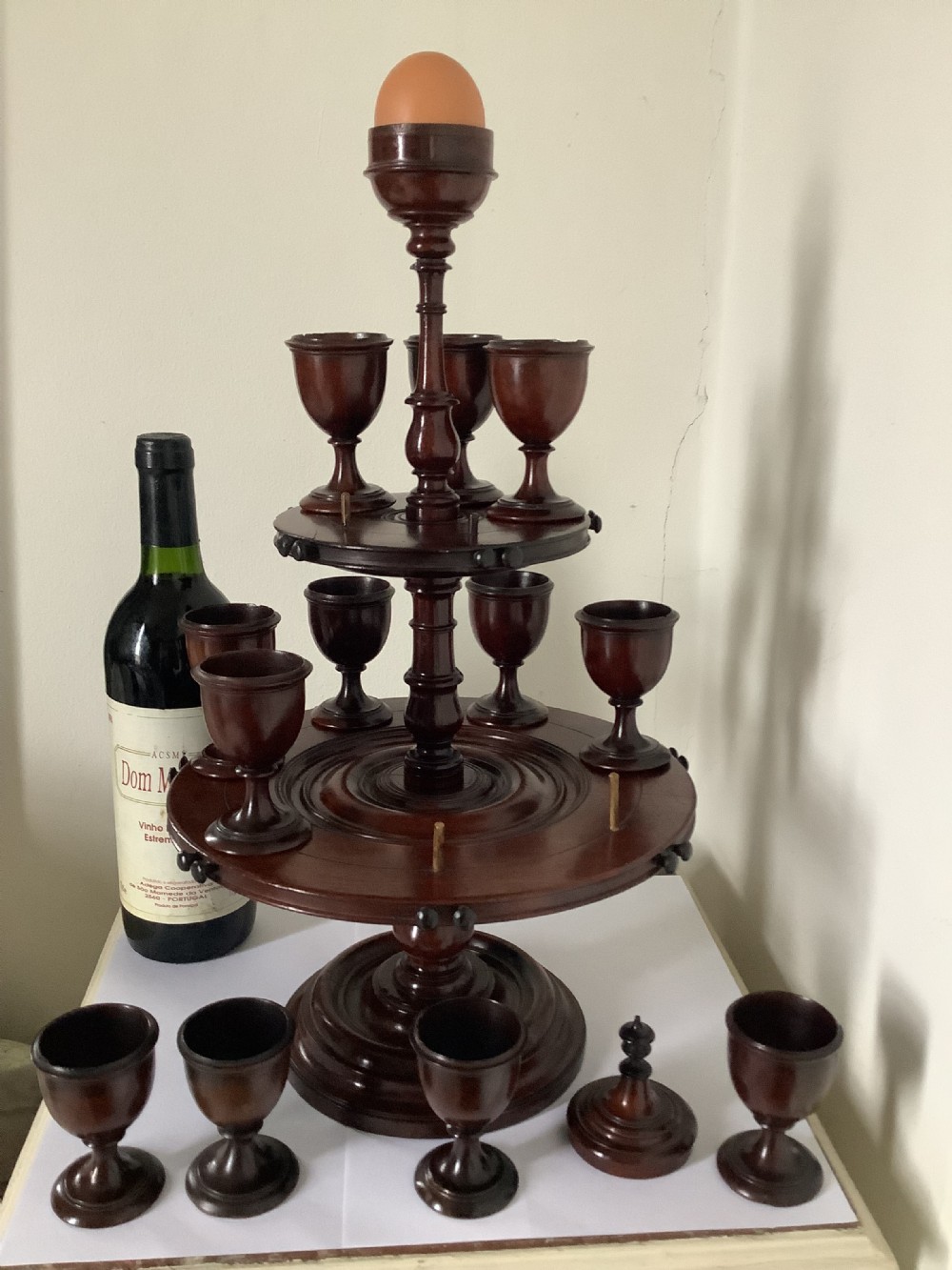 A dark turned mahogany two-tier revolving egg cup stand with a central finial and matching wooden egg cups. View III