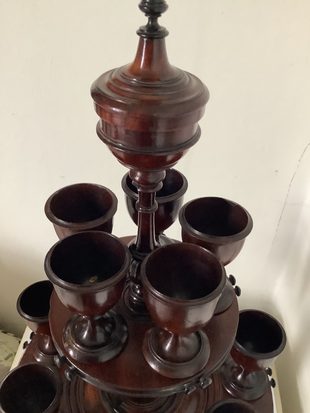 A dark turned mahogany two-tier revolving egg cup stand with a central finial and matching wooden egg cups. View IX
