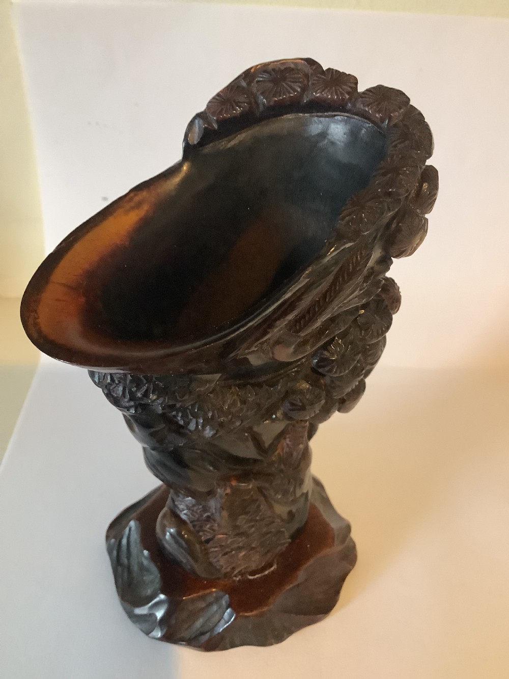 A deeply carved dark brown Chinese horn libation cup featuring intricate figural and floral relief details. View IV