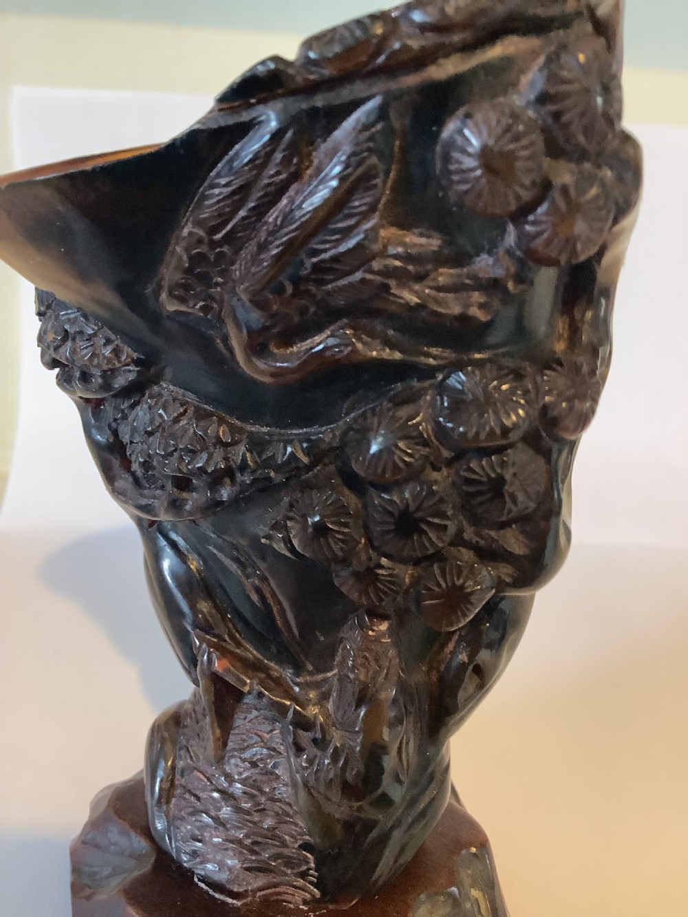 A deeply carved dark brown Chinese horn libation cup featuring intricate figural and floral relief details. View VI