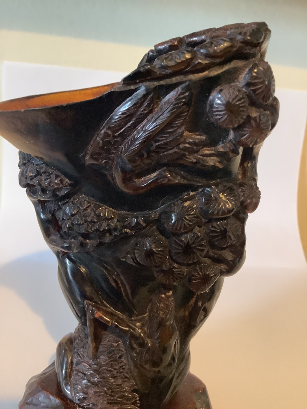 A deeply carved dark brown Chinese horn libation cup featuring intricate figural and floral relief details. View VIII