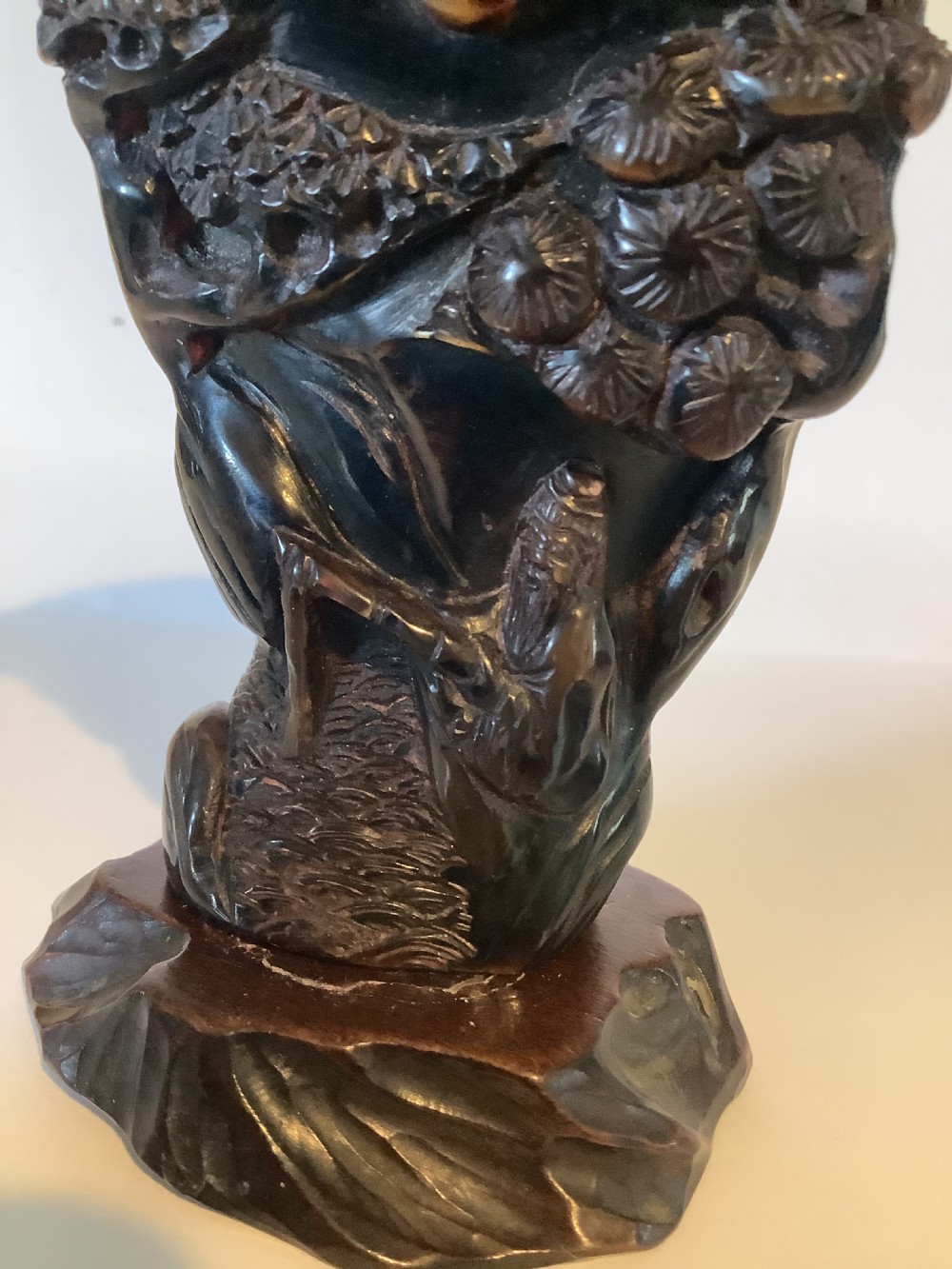 A deeply carved dark brown Chinese horn libation cup featuring intricate figural and floral relief details. View IX