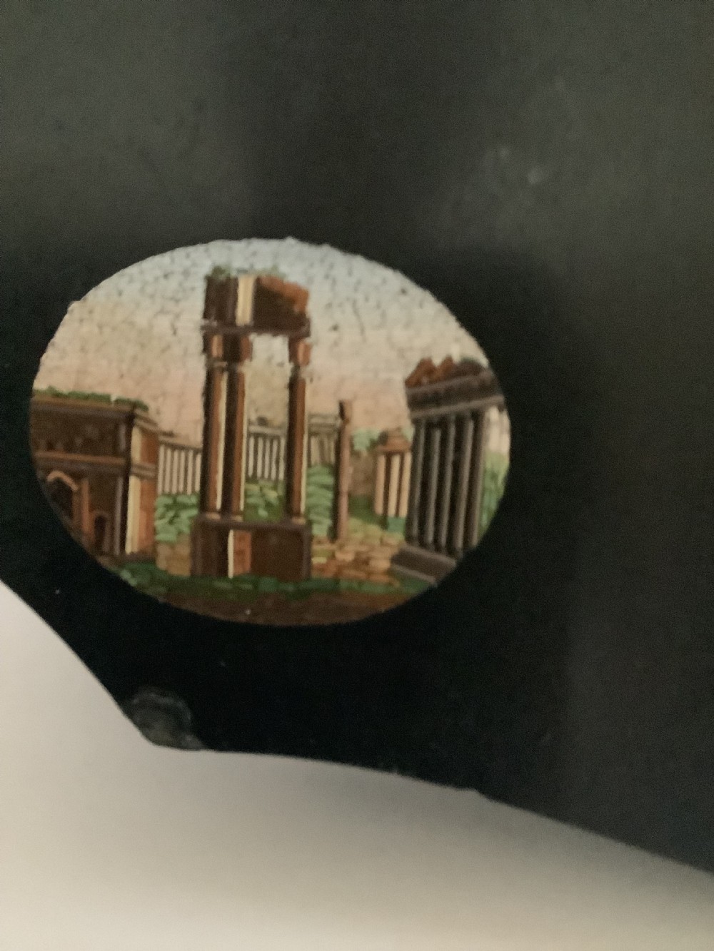 A shaped black marble plaque inlaid with five detailed micromosaic panels depicting classical Roman landmarks including Saint Peters Square and the Colosseum. View IV