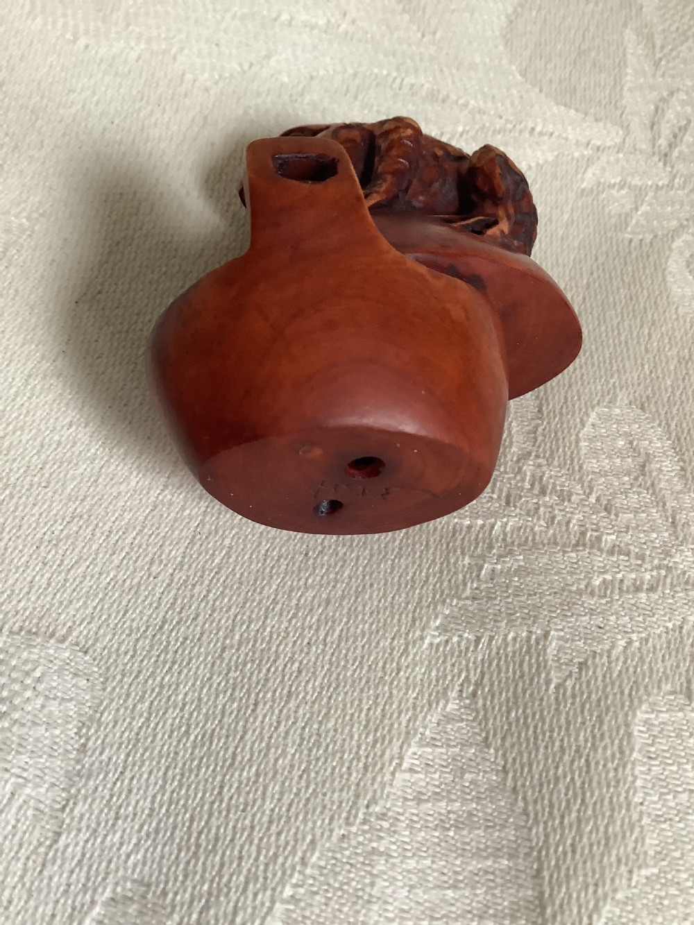 A dark brown carved wood netsuke shaped as a textured toad resting on a curved base. View VI