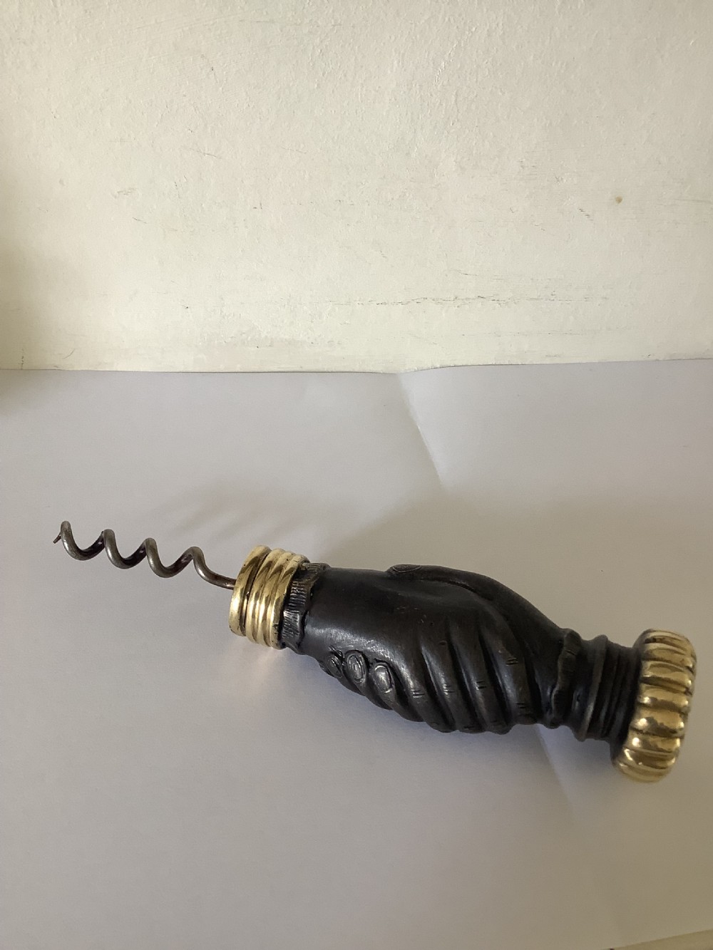 A cast brass and bronzed metal corkscrew featuring a handle formed in the shape of two clasped hands with a steel helix worm.