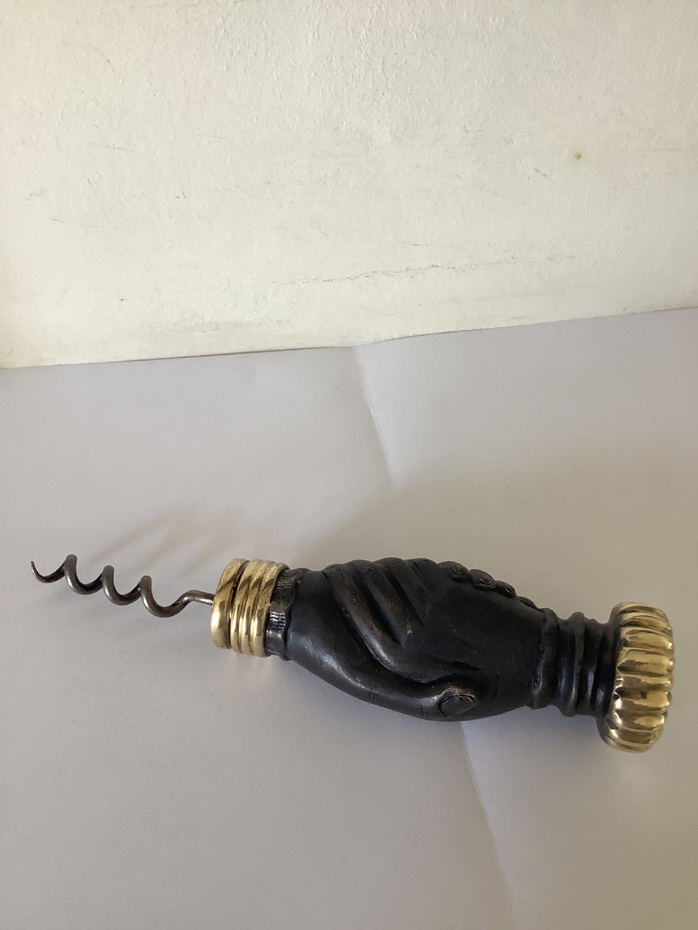 A cast brass and bronzed metal corkscrew featuring a handle formed in the shape of two clasped hands with a steel helix worm. View III