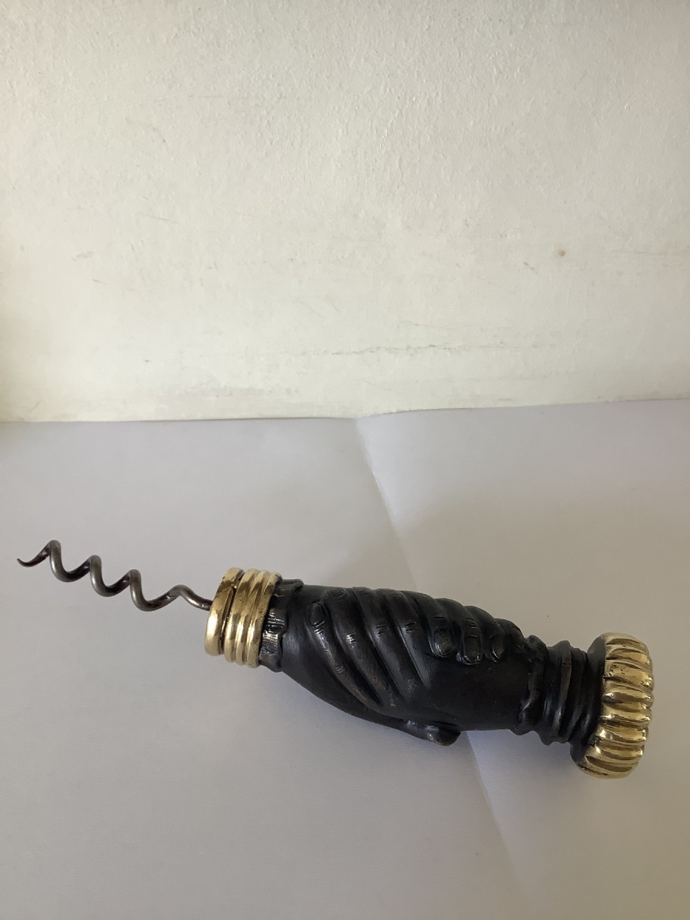 A cast brass and bronzed metal corkscrew featuring a handle formed in the shape of two clasped hands with a steel helix worm. View V