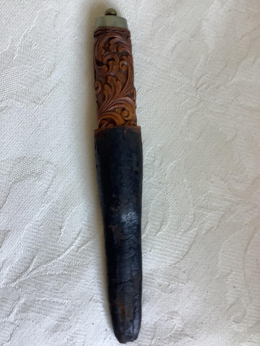 An antique Norwegian dagger featuring a carved wooden handle with acanthus leaf motifs, a steel blade, and an accompanying dark leather sheath. View VII