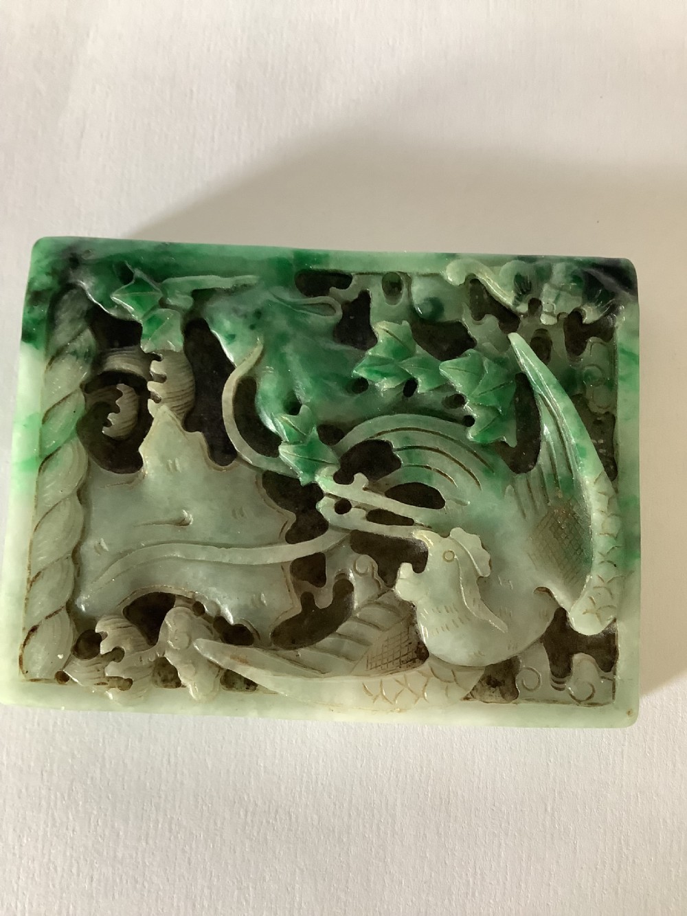 A rectangular openwork carved jade plaque featuring green and pale celadon tones with a carved bird and foliage motif. View X