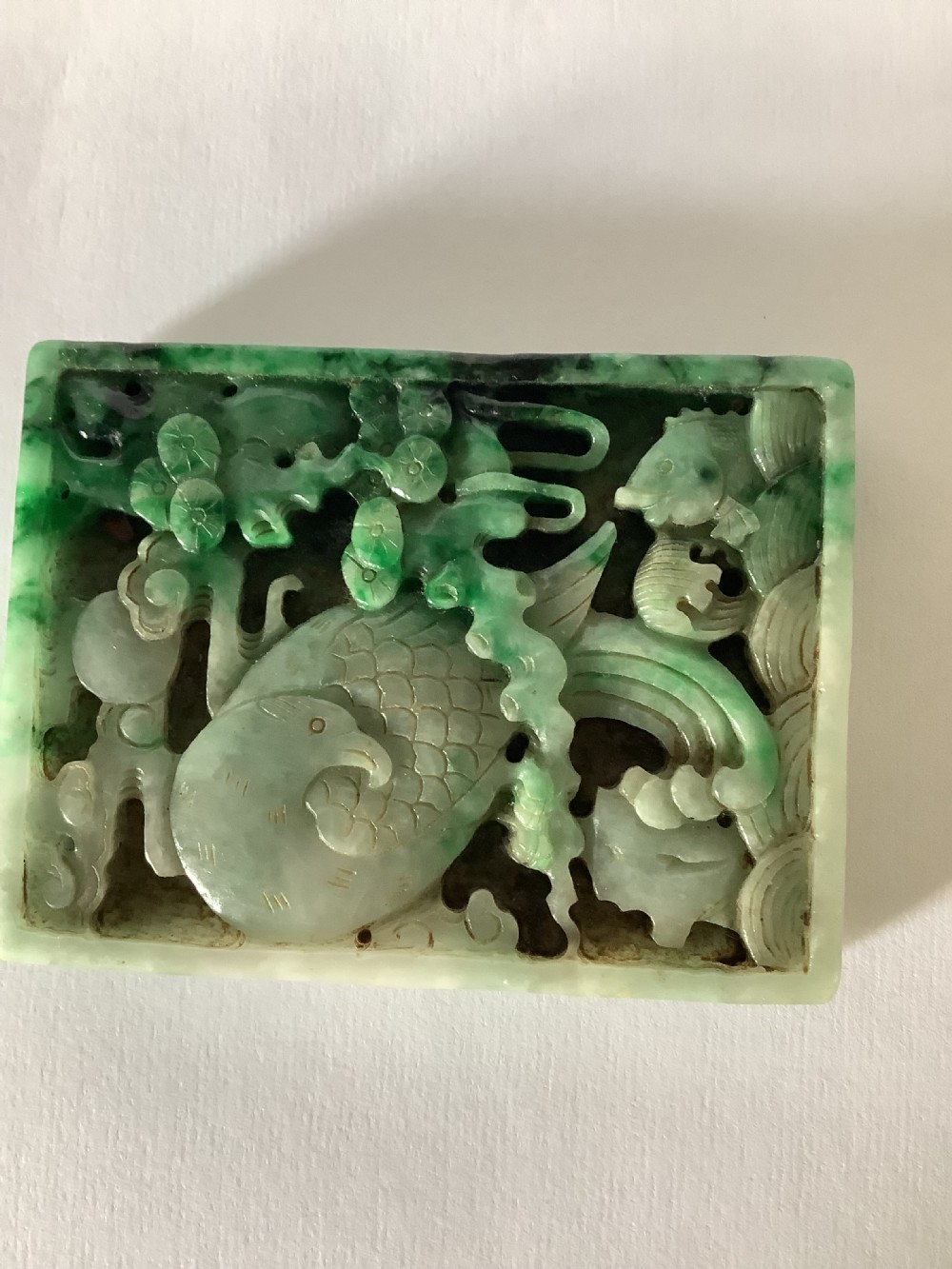 A rectangular openwork carved jade plaque featuring green and pale celadon tones with a carved bird and foliage motif. View II