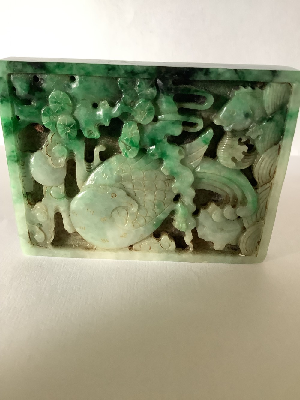 A rectangular openwork carved jade plaque featuring green and pale celadon tones with a carved bird and foliage motif. View III