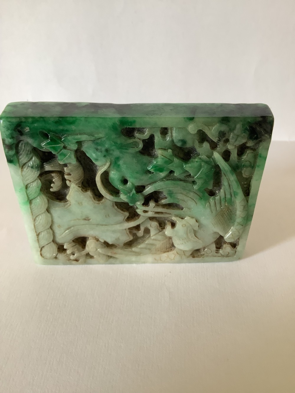 A rectangular openwork carved jade plaque featuring green and pale celadon tones with a carved bird and foliage motif. View V