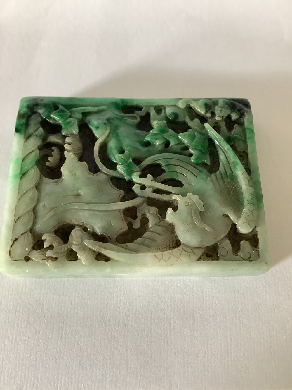 A rectangular openwork carved jade plaque featuring green and pale celadon tones with a carved bird and foliage motif. View VI