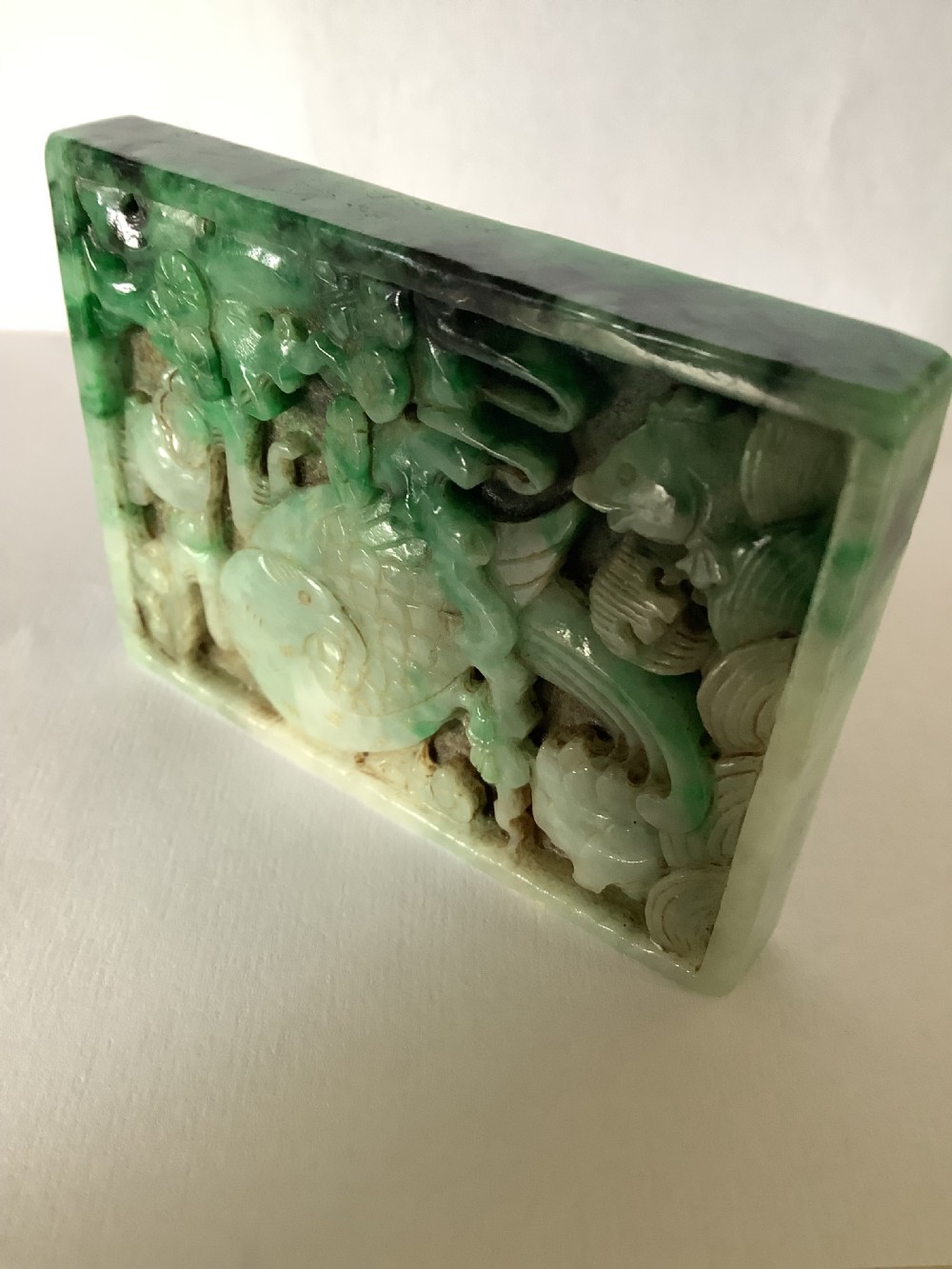 A rectangular openwork carved jade plaque featuring green and pale celadon tones with a carved bird and foliage motif. View XI