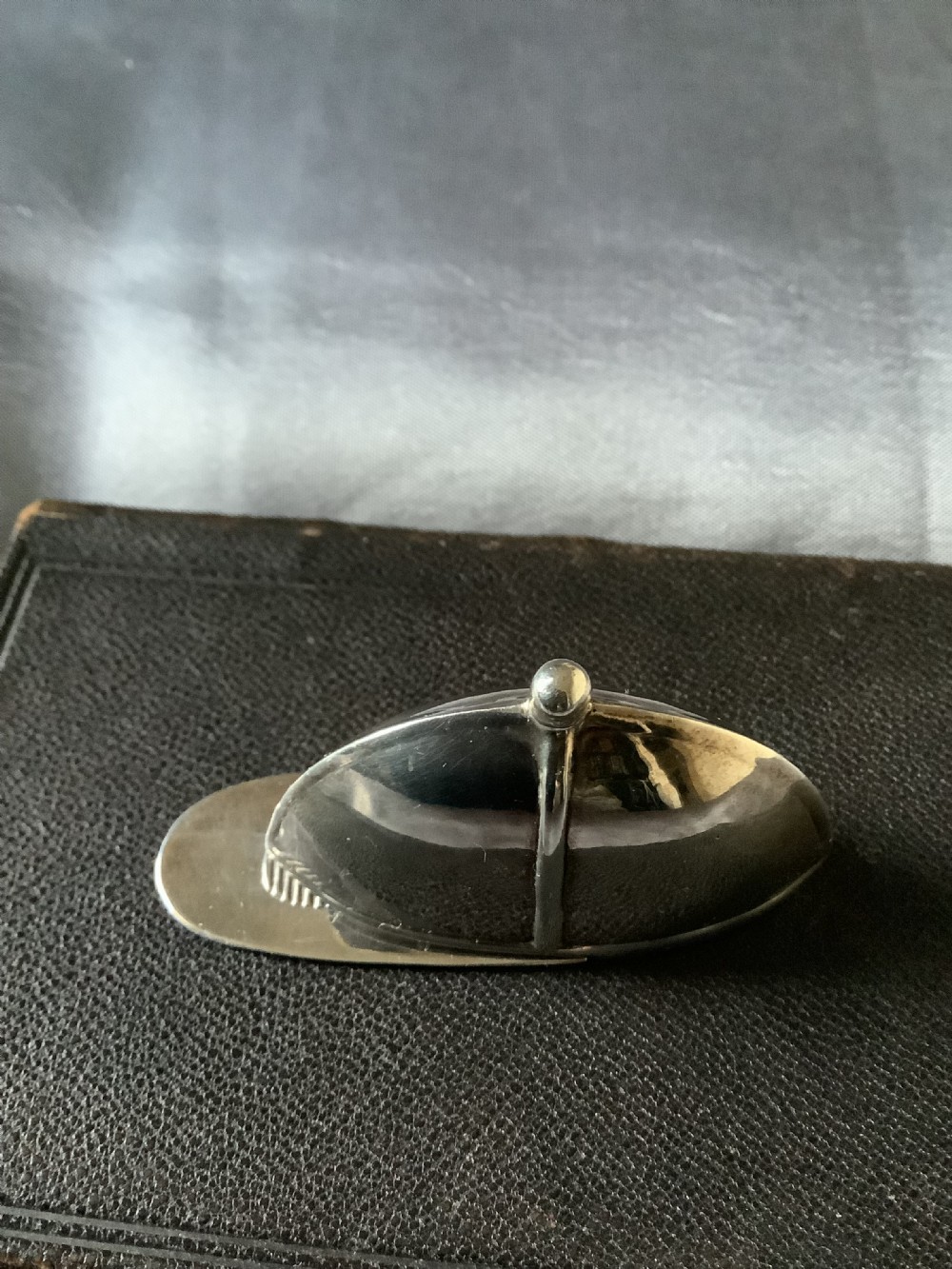 A sterling silver vesta case designed in the shape of an equestrian riding hat with a polished finish. View X