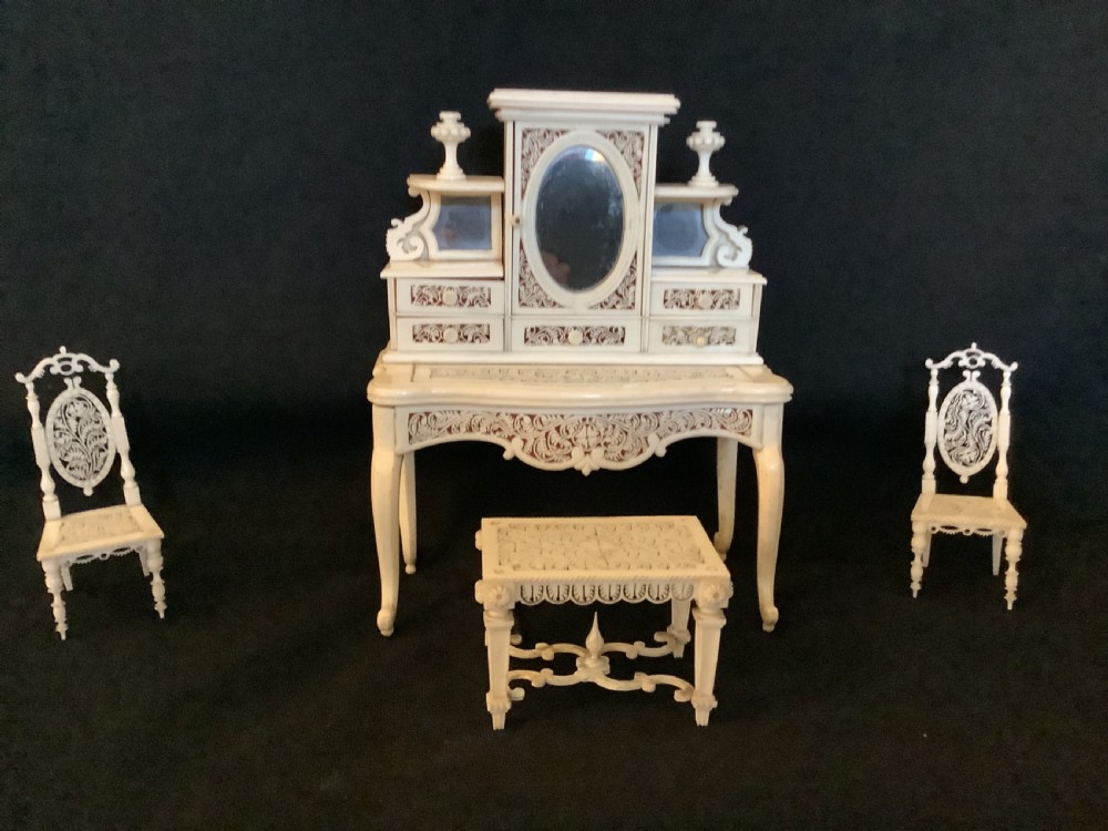 A miniature French carved bone boudoir suite featuring an ornate dressing table with mirror, a matching stool, and two side chairs with intricate pierced backs.