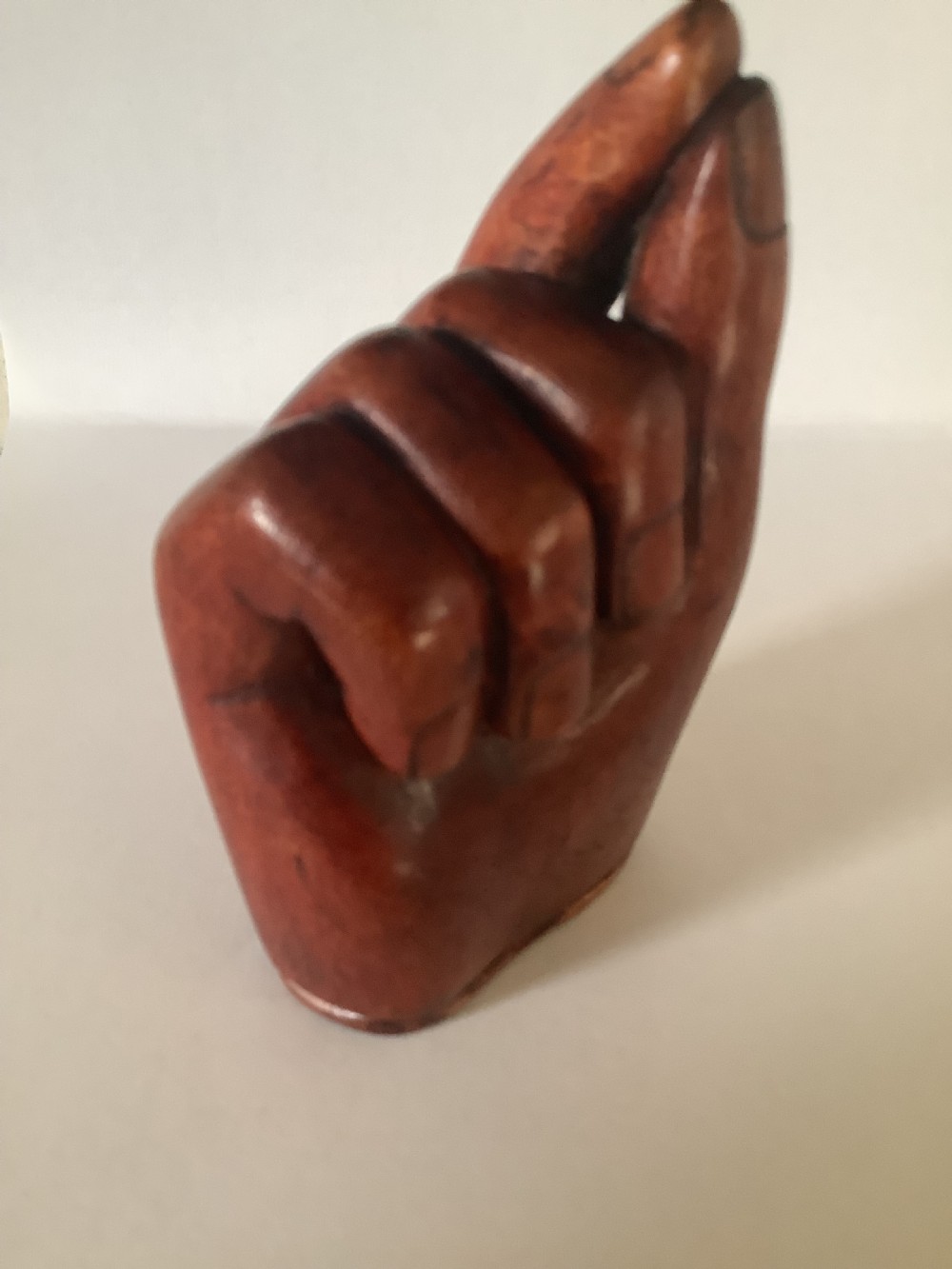 A nineteenth-century carved hardwood snuff box in the form of a hand holding a pinch of snuff, finished in a warm brown tone.