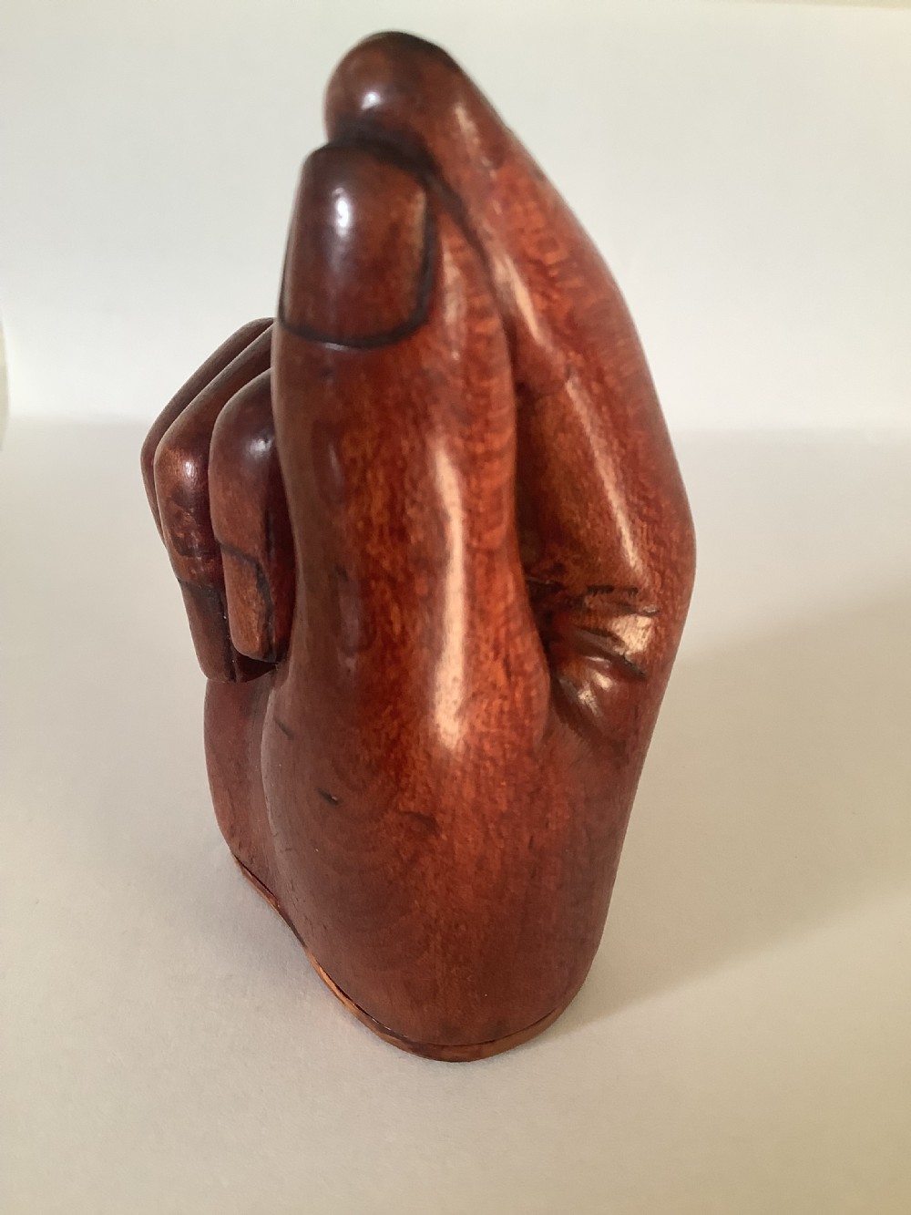 A nineteenth-century carved hardwood snuff box in the form of a hand holding a pinch of snuff, finished in a warm brown tone. View II
