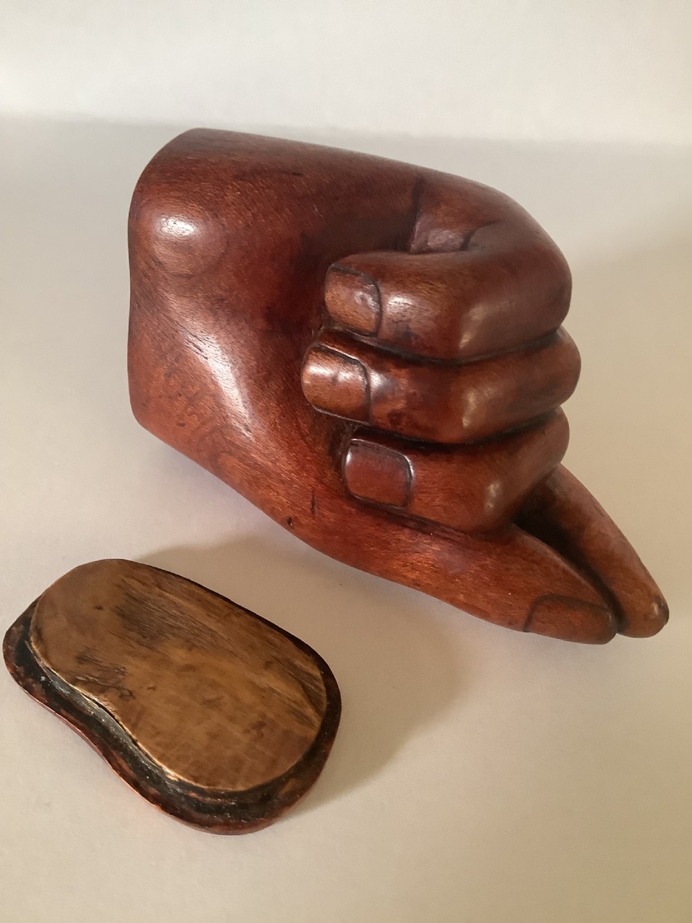 A nineteenth-century carved hardwood snuff box in the form of a hand holding a pinch of snuff, finished in a warm brown tone. View V