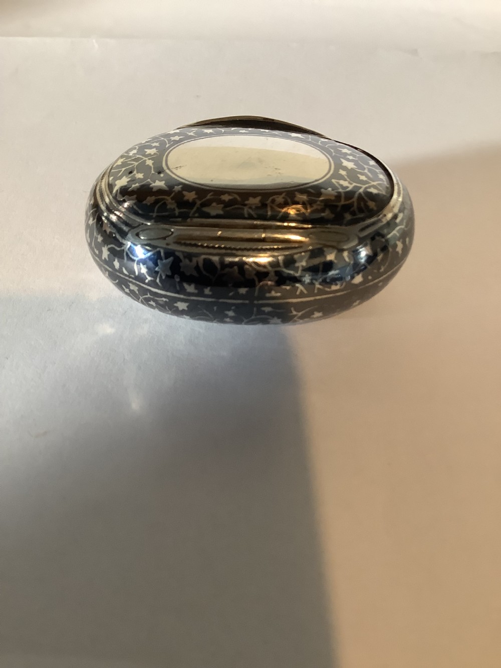 An oval silver-inlaid pocket snuff box featuring a foliage pattern and a central plain oval cartouche on the lid. View VII