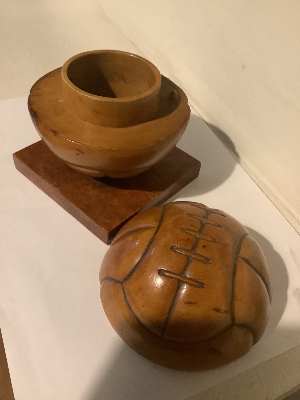 A carved hardwood lidded box shaped like a vintage laced football, mounted on a square burr wood base. View II