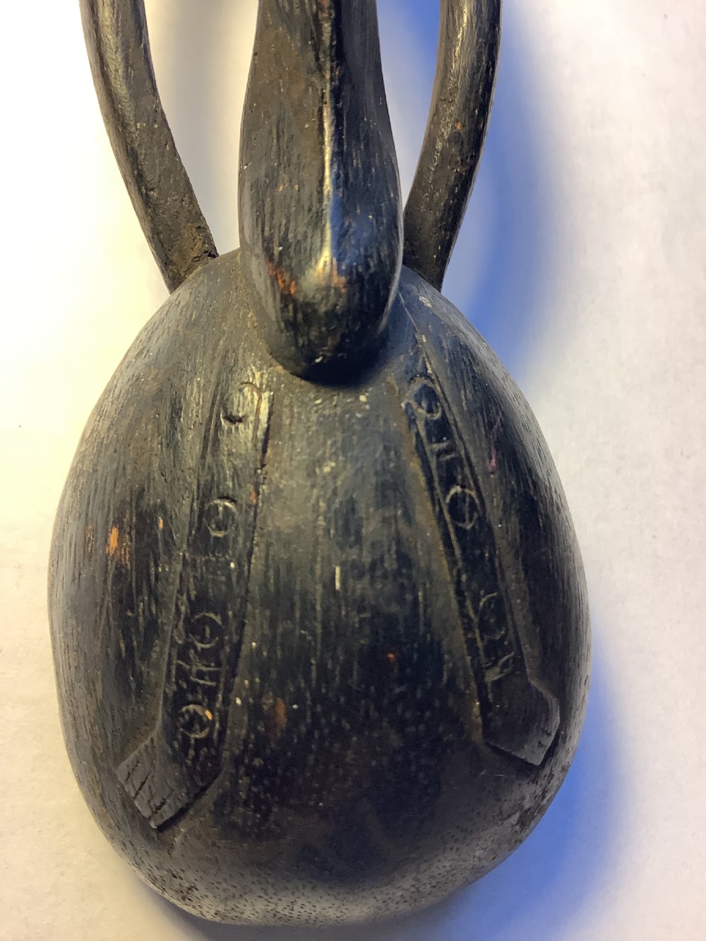 A dark carved wooden spoon featuring a handle sculpted into a stylized human figure with incised geometric markings along the arms. View VII