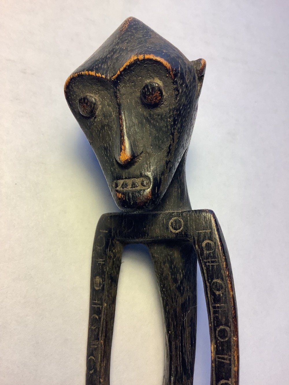 A dark carved wooden spoon featuring a handle sculpted into a stylized human figure with incised geometric markings along the arms. View VIII