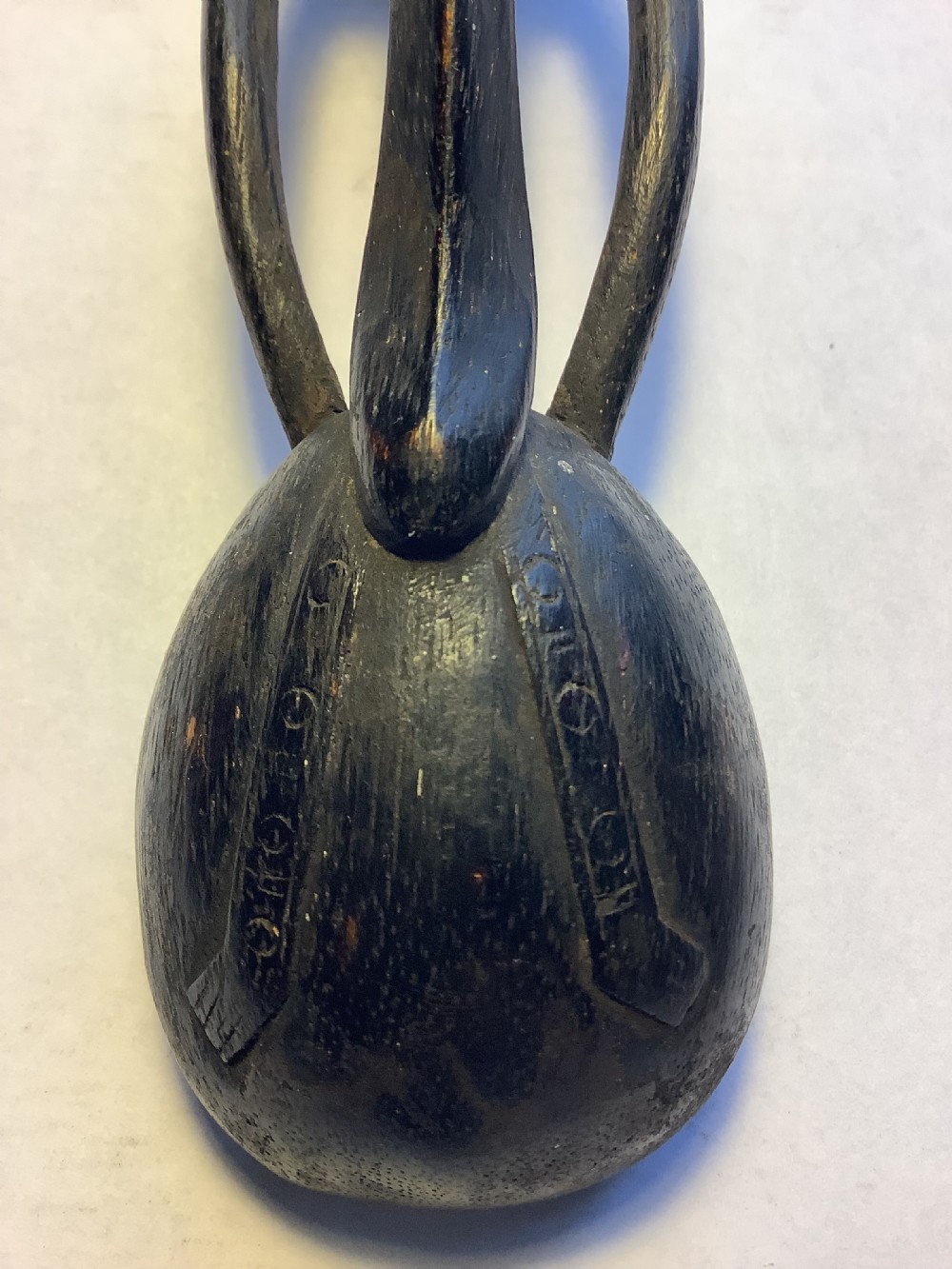 A dark carved wooden spoon featuring a handle sculpted into a stylized human figure with incised geometric markings along the arms. View XI