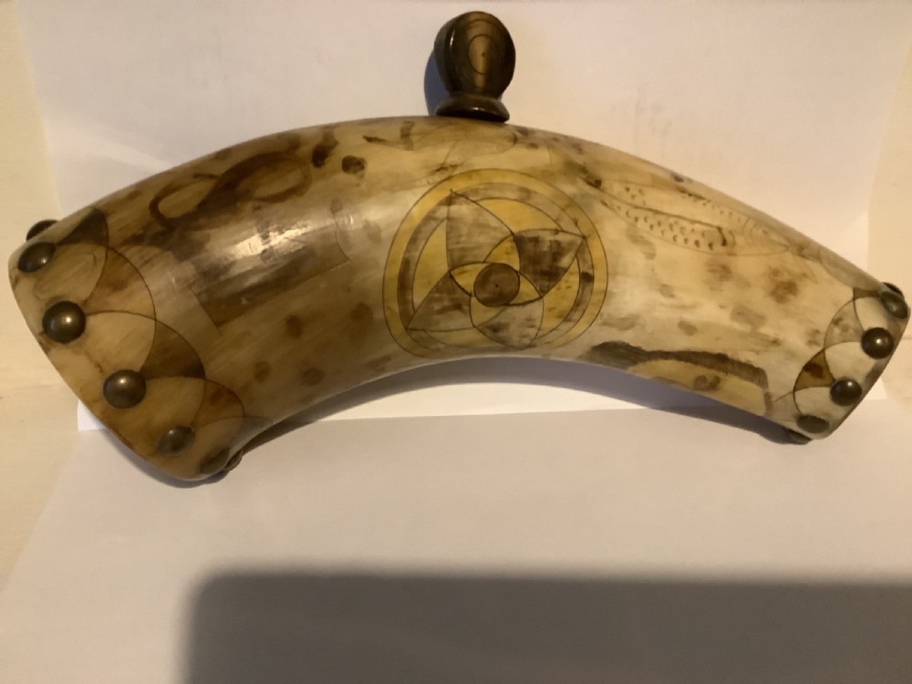 A curved antique powder horn featuring geometric scrimshaw engravings, brass studs along the borders, and a turned wooden plug. View III
