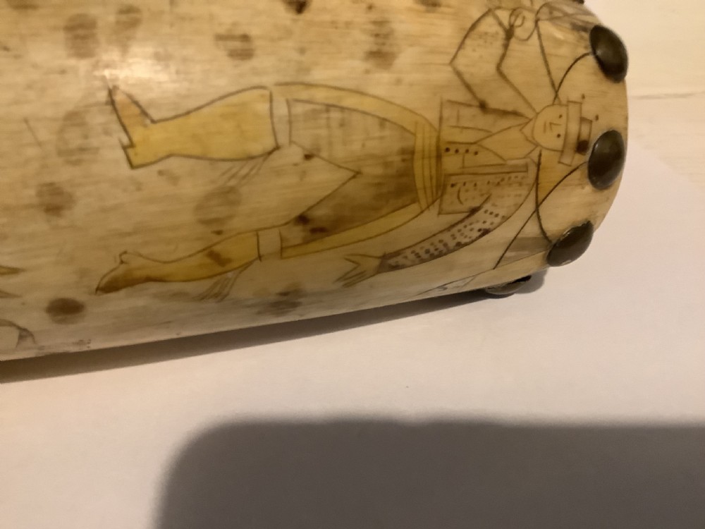 A curved antique powder horn featuring geometric scrimshaw engravings, brass studs along the borders, and a turned wooden plug. View IX
