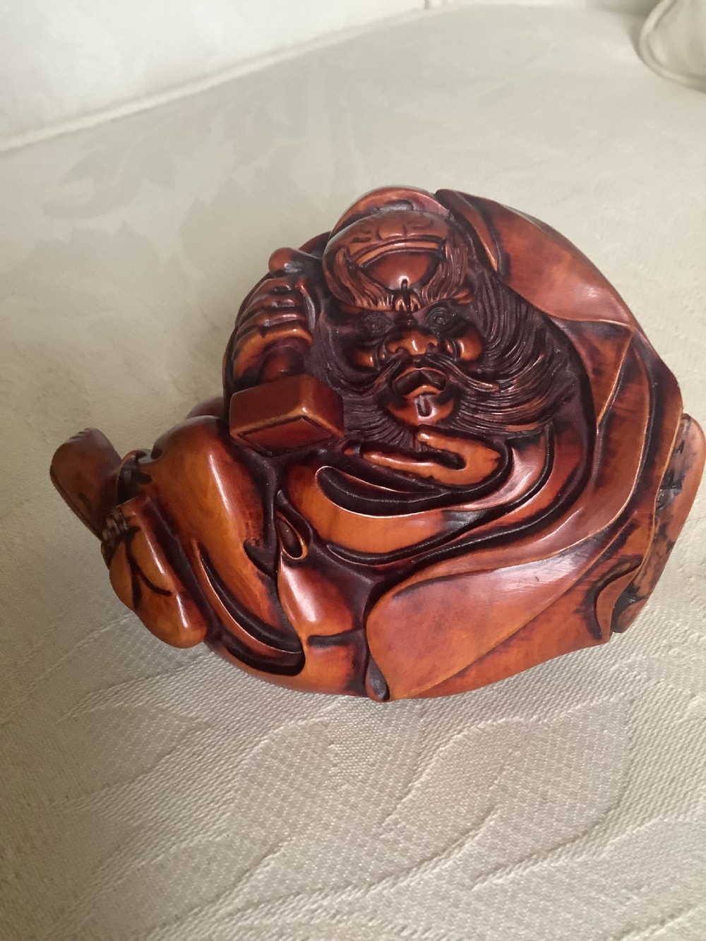 A Japanese hand-carved wooden figure depicting a bearded man in flowing robes with a smooth polished brown finish.