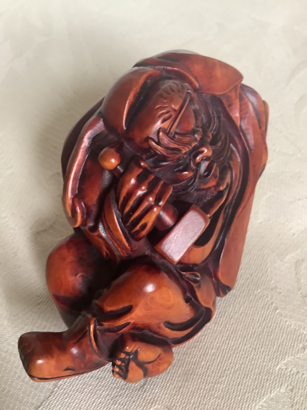 A Japanese hand-carved wooden figure depicting a bearded man in flowing robes with a smooth polished brown finish. View V