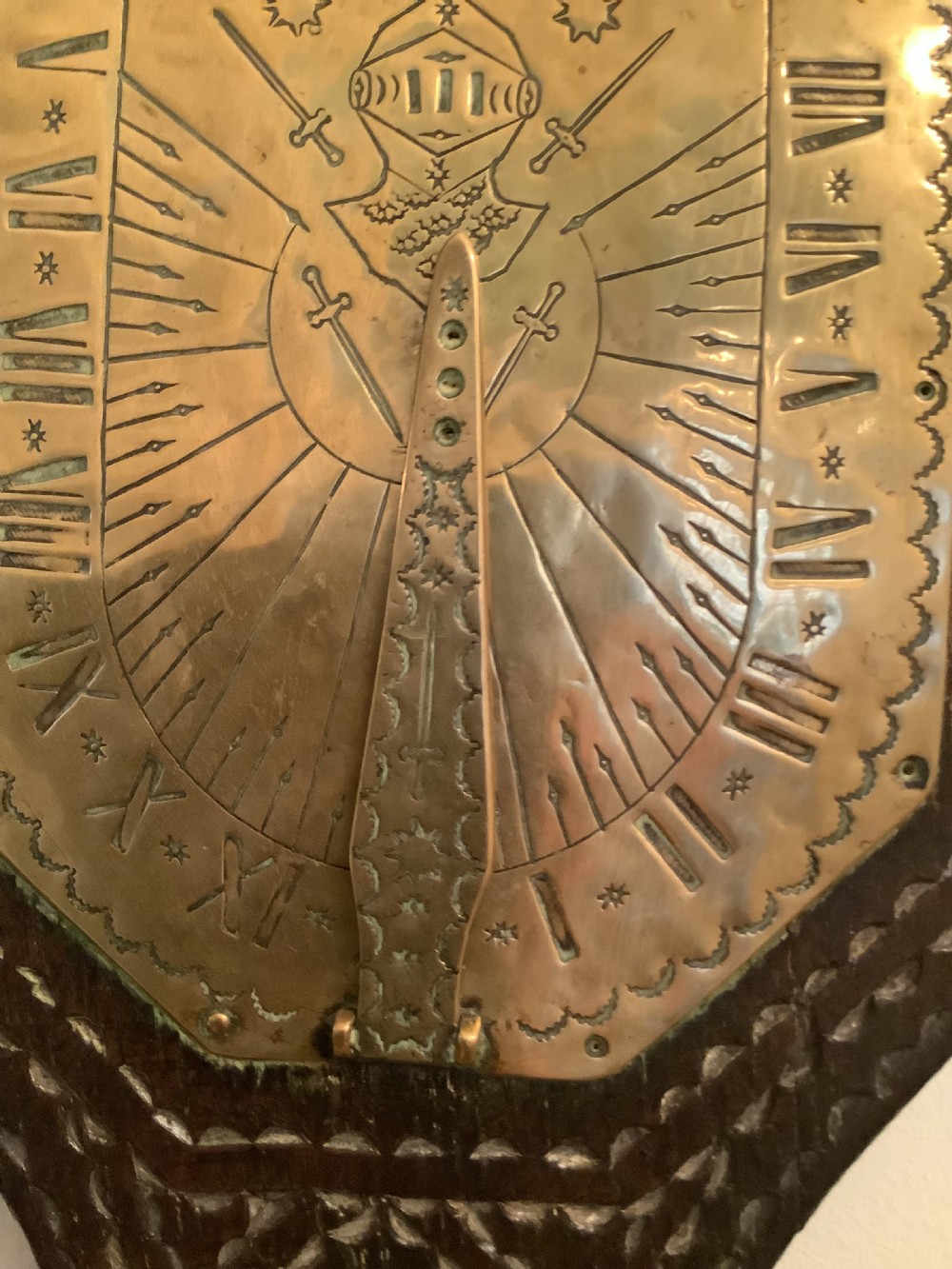 An antique brass sundial and world clock plaque mounted on a carved dark wooden backboard, featuring engraved Roman numerals and global place names. View XII