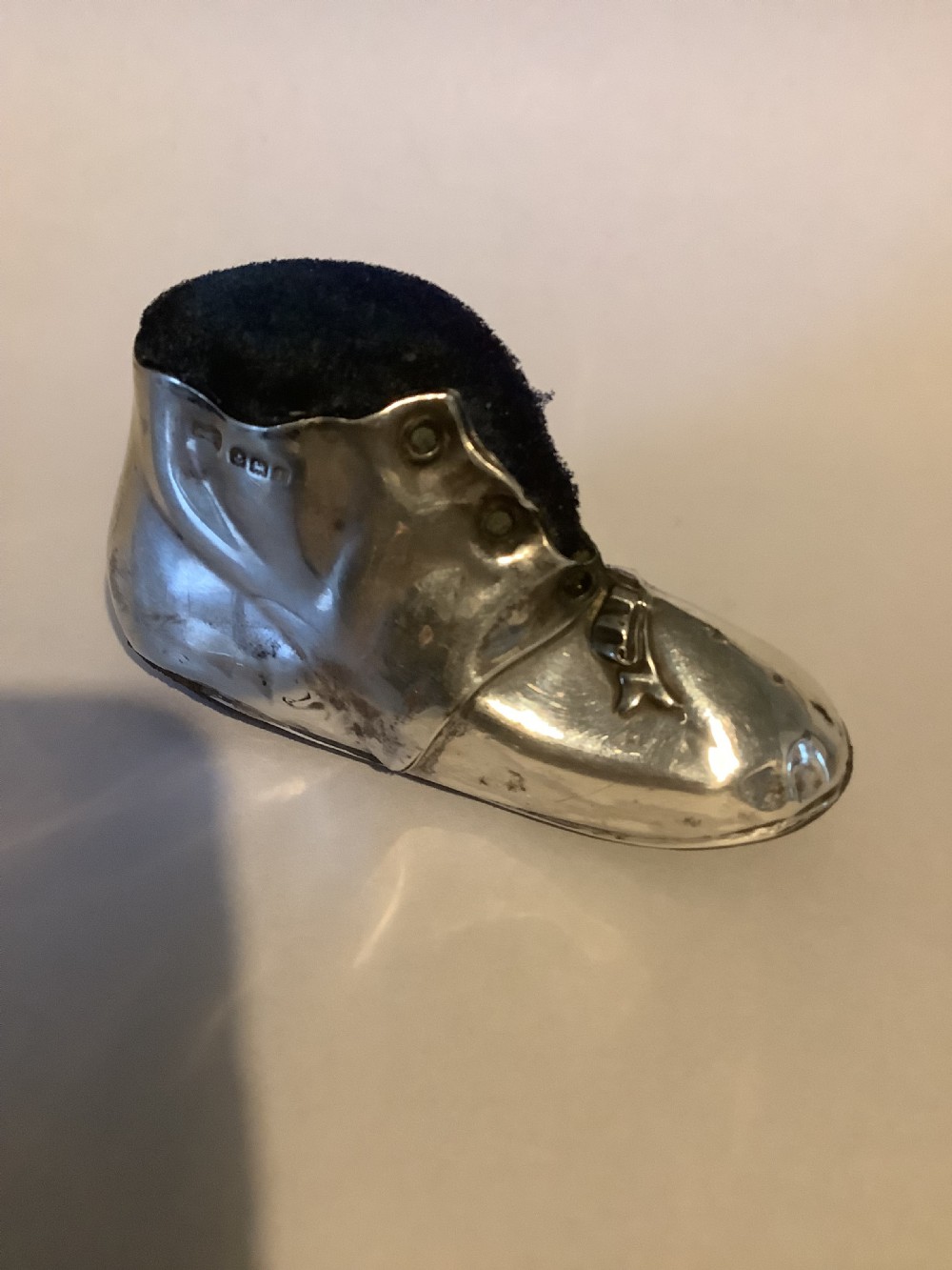 An antique silver pin cushion shaped like a laced boot with a dark velvet top insert. View II