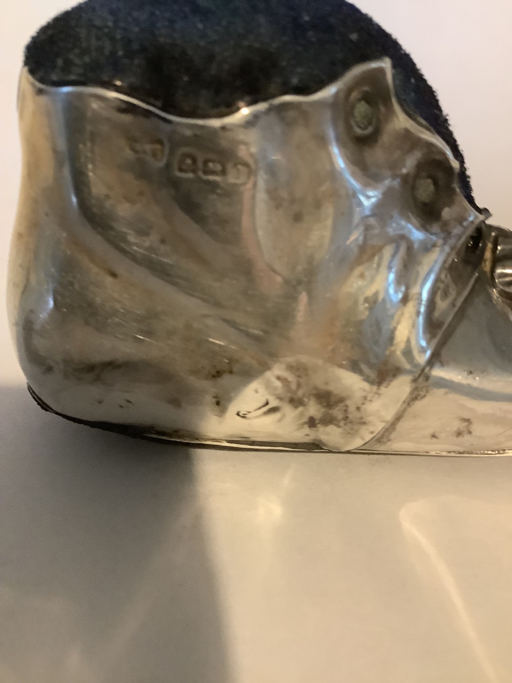 An antique silver pin cushion shaped like a laced boot with a dark velvet top insert. View IV