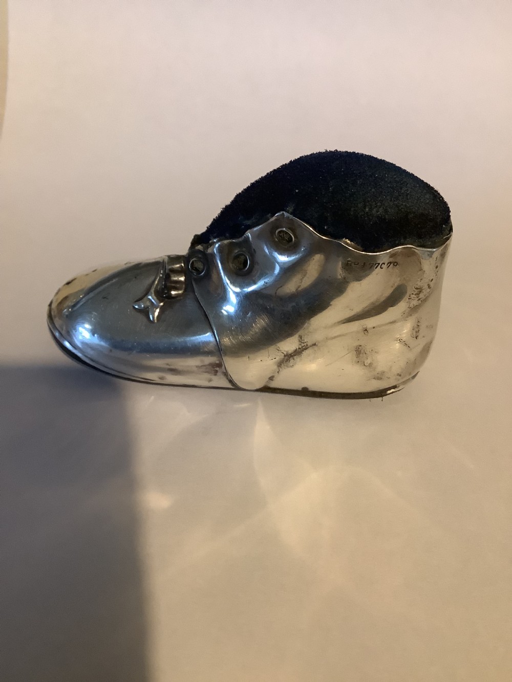 An antique silver pin cushion shaped like a laced boot with a dark velvet top insert. View VI